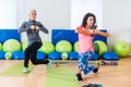 Fit female sportswoman doing curtsy lunge exercise with dumbbells in group fitness studio class