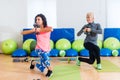 Fit female sportswoman doing curtsy lunge exercise with dumbbells in group fitness studio class Royalty Free Stock Photo