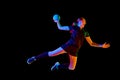 Fit, focused woman engaged in handball drills, displaying determination and focus against black background in mixed neon Royalty Free Stock Photo