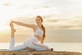 Fit girl doing stretching exercise on see background. Pretty young woman practicing yoga at the beach on sunrise Royalty Free Stock Photo