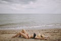 Fit girl in hat lying on beach. Fashionable young woman covering with straw hat, relaxing on sandy beach near sea. Summer vacation Royalty Free Stock Photo