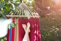 Fit girl is lying in the colourful hammock. Woman with beautiful legs is relaxing in hippie style garden near the village house.