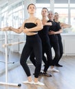 Fit girl performing demi plie at barre in ballet studio