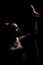 Fit girl practicing yoga in a studio. Half silhouette side lit fitness model