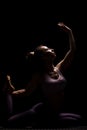 Fit girl practicing yoga in a studio. Half silhouette side lit fitness model