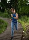 Sporty young woman jogging smiling in park forest on path Royalty Free Stock Photo