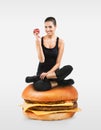 Fit girl sitting on a hamburger holding an apple Royalty Free Stock Photo