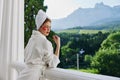 a fit girl in a white robe the balcony overlooks the mountains looking on the view