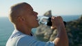 Fit guy drinking water in sunlight stunning ocean view closeup. Tired man close