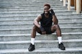 Fit happy sporty young black man boxer fighter sitting at urban stairs outdoors. Royalty Free Stock Photo