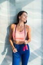 Fit happy woman in sportswear holding jump rope at home in bright room Royalty Free Stock Photo