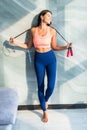 Fit happy woman in sportswear holding jump rope at home in bright room Royalty Free Stock Photo