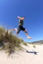 Fit, healthy middle aged man leaping over sand dunes