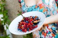 Fit and healthy woman holding her breakfast plate, oatmeal porridge with fresh berries and nuts, sprinkled by maca powder