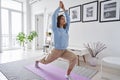 Fit healthy young woman doing yoga warrior exercise standing at home. Royalty Free Stock Photo
