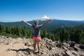 Female hiker stands on the summit of Tom and Harry Mountain in Mt. Hood National Forest, with her arms held up, looking at Mo