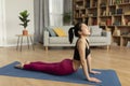 Fit korean lady doing yoga cobra pose or pilates, working out on mat in living room interior, copy space Royalty Free Stock Photo