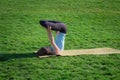 Fit lady practicing yoga asans on the yoga mat laying in gren grass Royalty Free Stock Photo