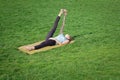 Fit lady practicing yoga asans on the yoga mat laying in gren grass Royalty Free Stock Photo