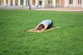 Fit lady practicing yoga asans on the yoga mat laying in gren grass Royalty Free Stock Photo