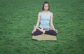 Fit lady practicing yoga asans on the yoga mat laying in gren grass Royalty Free Stock Photo