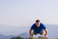 Fit male athlete doing pushups at the edge of a cliff while enjoying the amazing view Royalty Free Stock Photo