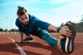 Man runner stretching legs preparing for run training on stadium tracks doing warm-up Royalty Free Stock Photo