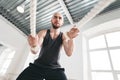 Strong fitness sportsman using training ropes for exercise at gym