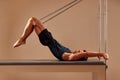 Fit man doing a lunge stretch yoga pilates exercise to strengthen and tone his muscles using a reformer in gym. Health Royalty Free Stock Photo