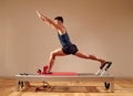 Fit man doing a lunge stretch yoga pilates exercise to strengthen and tone his muscles using a reformer in gym. Health Royalty Free Stock Photo