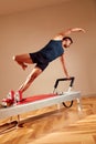 Fit man doing a lunge stretch yoga pilates exercise to strengthen and tone his muscles using a reformer in gym. Health Royalty Free Stock Photo