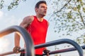 Fit man doing triceps dips on parallel bars at park exercising outdoors Royalty Free Stock Photo