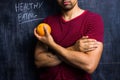 Fit man holding a grapefruit in front of blackboard Royalty Free Stock Photo