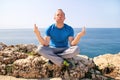 A fit man in the Lotus position on a seashore. Young fitness man doing yoga outdoors.