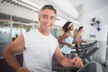 Fit man running on treadmill smiling at camera Royalty Free Stock Photo