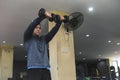 A fit man in a sweatshirt does double front dumbbell raises at an open air gym. Strict isolation shoulder workout for front delts