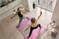 Fit middle aged family couple doing warrior yoga exercise at home.