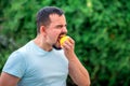Fit middle-aged man biting yellow lemon. Portrait of handsome man eating lemon outdoors. Tough decisions and mental health concept