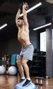 Fit and muscular man exercising with medicine ball on gymnastic hemisphere bosu ball in gym Royalty Free Stock Photo