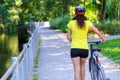 Fit muscular woman wheeling her bicycle outdoors