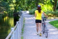 Fit muscular woman wheeling her bicycle outdoors