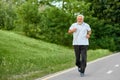 Fit old man running on racetrack in green park. Royalty Free Stock Photo