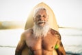 Fit senior male having fun surfing during sunset time - Retired man training with surfboard on the beach Royalty Free Stock Photo