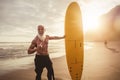 Fit senior male having fun surfing during sunset time - Retired man training with surfboard on the beach Royalty Free Stock Photo