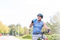 Fit senior man drinking water while riding bicycle in park Royalty Free Stock Photo