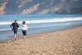 Fit senior wife and husband running along ocean coast Royalty Free Stock Photo