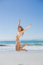 Fit smiling woman in white bikini leaping on beach Royalty Free Stock Photo