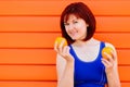 Fit smiling young woman with two oranges against colored wall. Freshness, woman health and wellness concept. Room for text Royalty Free Stock Photo