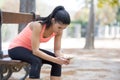 Fit sport woman looking at mobile phone internet app tracking performance after running workout sitting on park bench happy Royalty Free Stock Photo