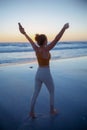 Fit sports woman rejoicing at beach at sundown
